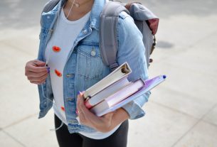 Une adolescente en tenue civile avec des cahiers en main.
