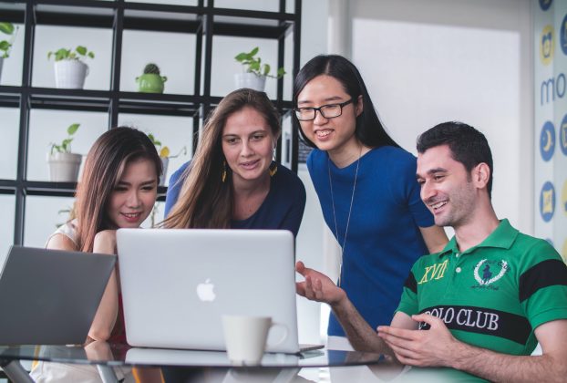 Un groupe de jeunes femmes et d'homme autour d'un ordinateur.